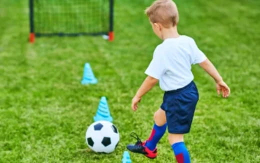 a young boy playing with a football ball