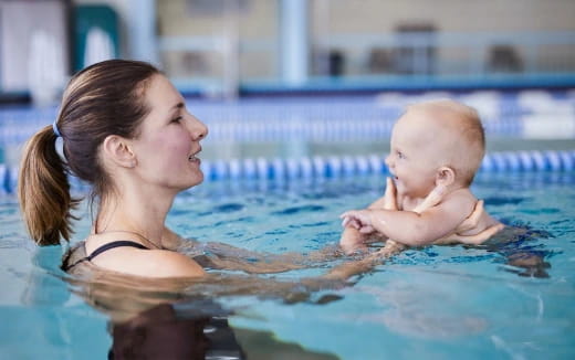a woman holding a baby in a pool