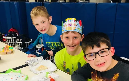 a group of boys sitting at a table with a birthday cake
