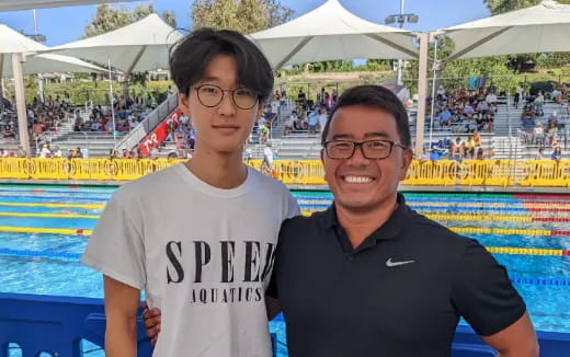 two men standing next to a pool