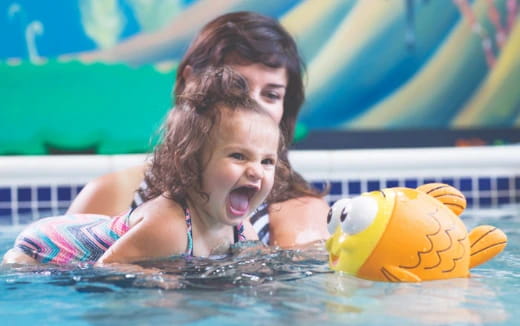 a baby in a pool with a toy duck