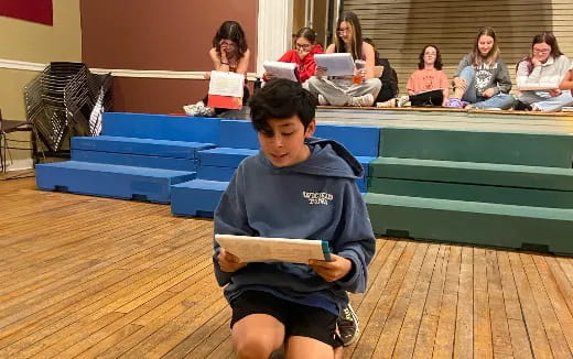 a boy sitting on the floor with a book in his hand