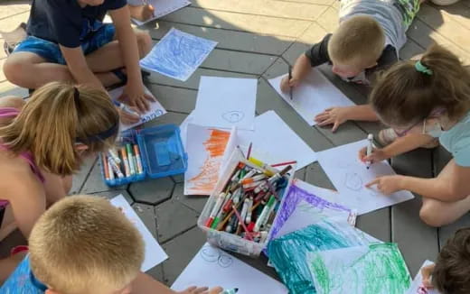 a group of children sitting at a table with papers and pencils