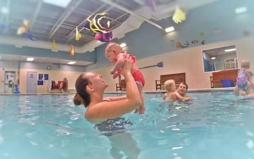 a person holding a baby in a swimming pool