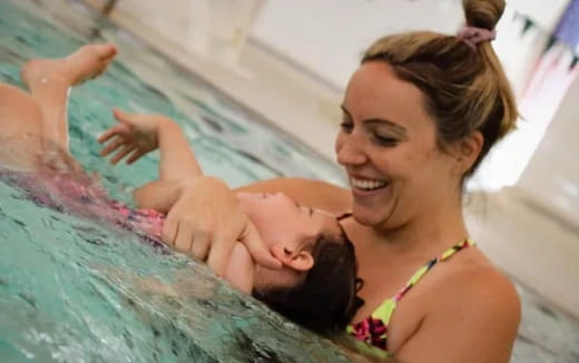 a woman holding a baby in a pool