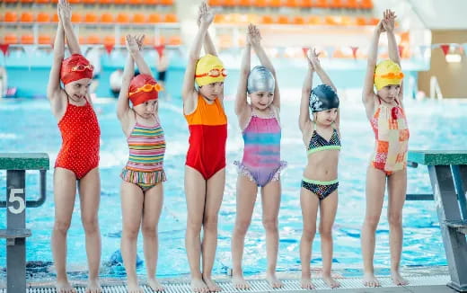 a group of children in swimsuits standing on a pool