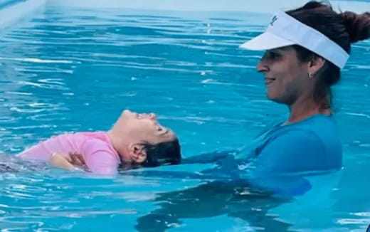 a person holding a baby in a pool