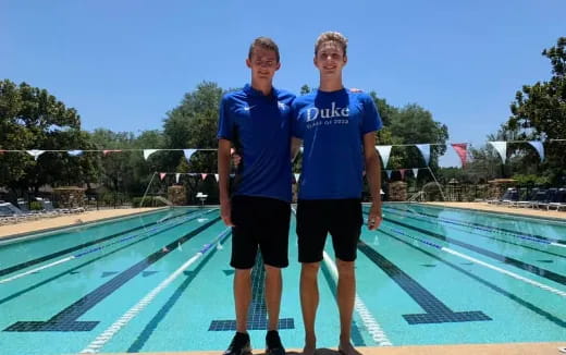 two men standing next to a pool
