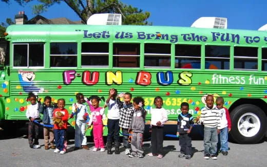 a group of children posing in front of a green bus