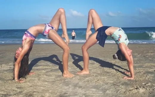 a man and woman doing handstands on a beach