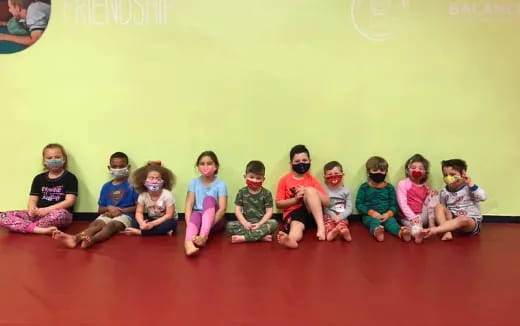 a group of children sitting on the floor wearing masks