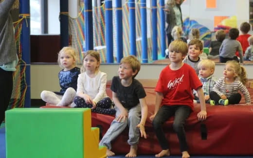 a group of children sitting on a red couch