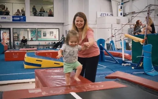 a woman and a child on a mat in a gym