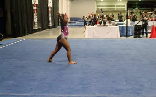 a person in a leotard dancing on a blue mat