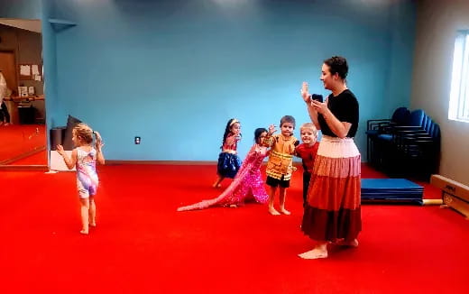 a woman and a group of children dancing on a red carpet