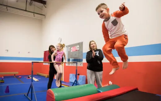 a person jumping on a trampoline with a group of women