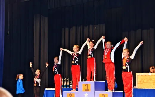 a group of children in red and black uniforms on a stage
