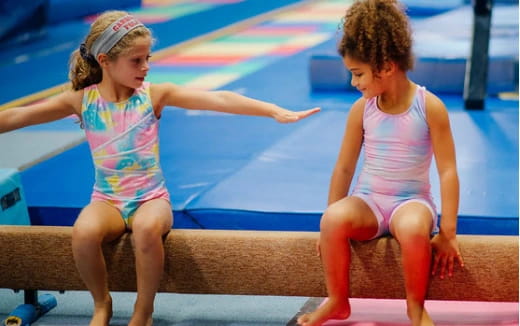 a couple of girls in swimsuits on a bench