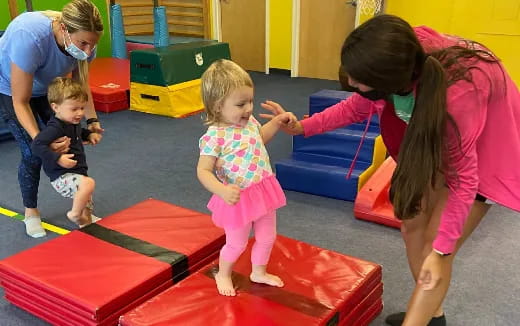 a person and children playing on a mat