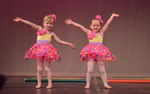 two girls wearing colorful dresses and dancing