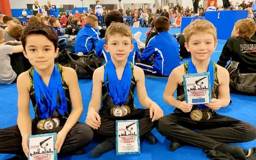 a group of boys sitting on the floor holding awards