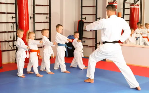 a person in white karate uniform with a group of boys in white karate uniforms