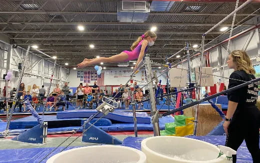 a person jumping on a trampoline in a large indoor pool