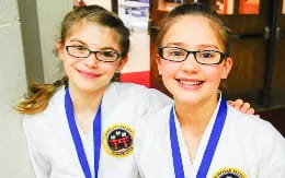 a couple of girls wearing white lab coats and smiling at the camera