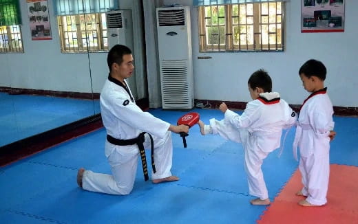 a person and two boys in karate uniforms