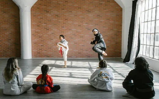 a group of people sitting on the floor watching a person in a mask