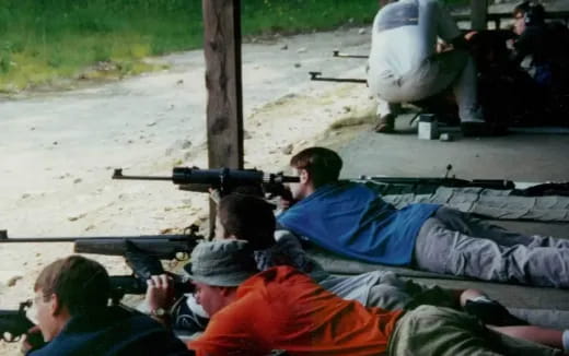 a group of people sitting on the ground with a rifle