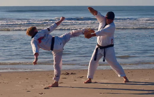 a couple of people in karate uniforms on a beach