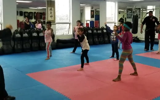 a group of children dancing in a room with a red carpet