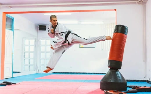 a person in a karate uniform kicking a punching bag