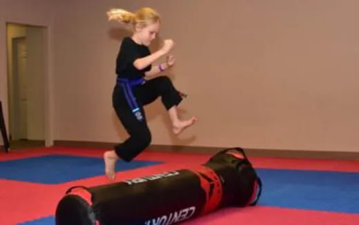 a woman jumping on a mat