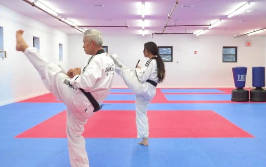 a man and a woman in karate uniforms in a room with blue and white mats