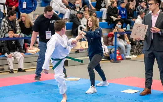 a man and a woman in karate uniforms with a crowd watching