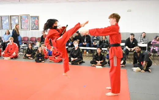 a man and woman in red karate uniforms with a crowd watching