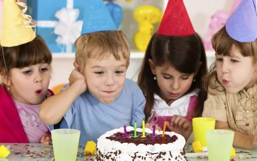 a group of children around a birthday cake
