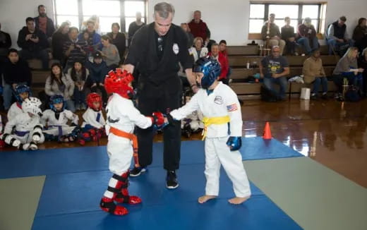 a man standing next to kids in karate uniforms