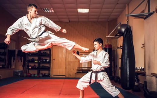 a person and a boy in karate uniforms in a room with a red floor and a wood floor