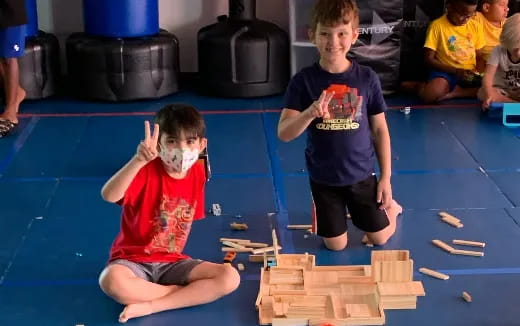 a group of kids playing with wooden blocks on a blue floor