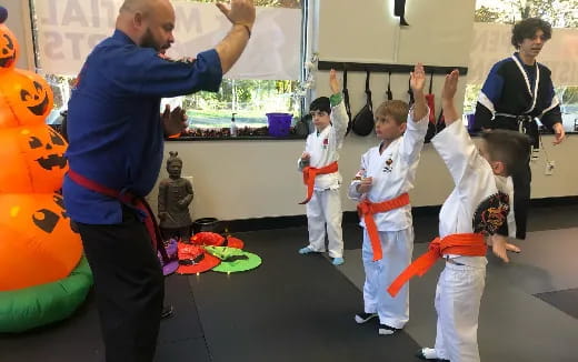 a person standing in front of a group of kids in karate uniforms