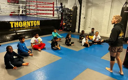 a person standing in front of a group of people sitting on the ground