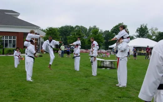 a group of people in white karate uniforms on grass