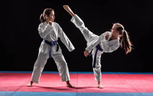 a man and a woman in karate uniforms on a red surface