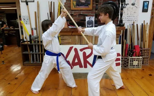 a couple of kids in karate uniforms practicing in a room