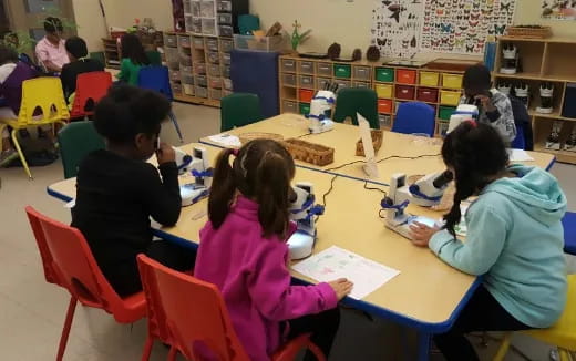 a group of children sitting at a table in a classroom