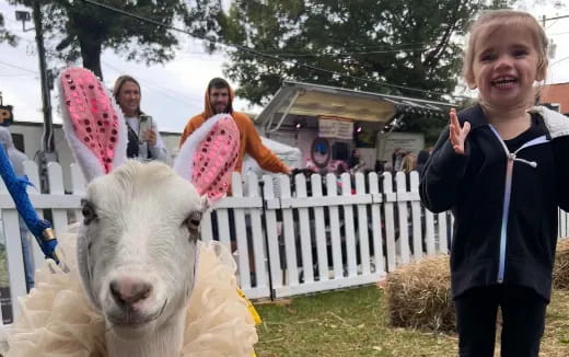 a girl standing next to a goat