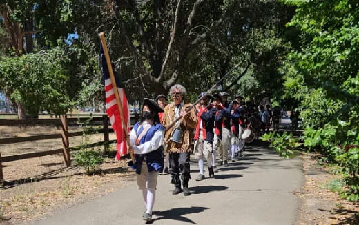 a group of people walking down a path with a flag